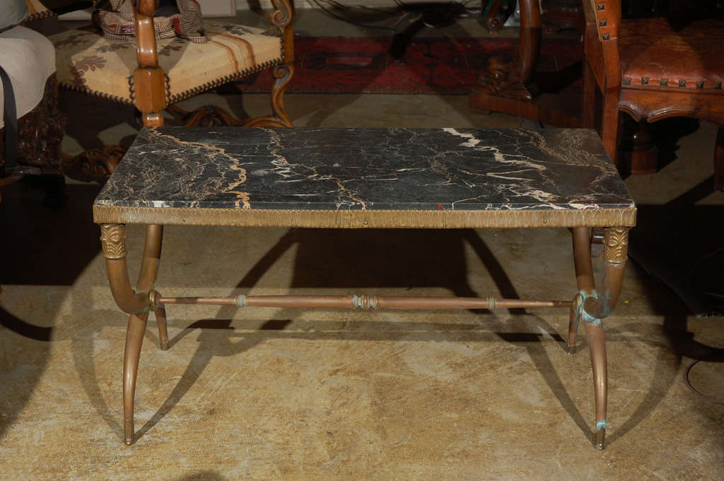 Brass frame coffee table adorned with medallions, faux capitals and a black and white marble top. 
