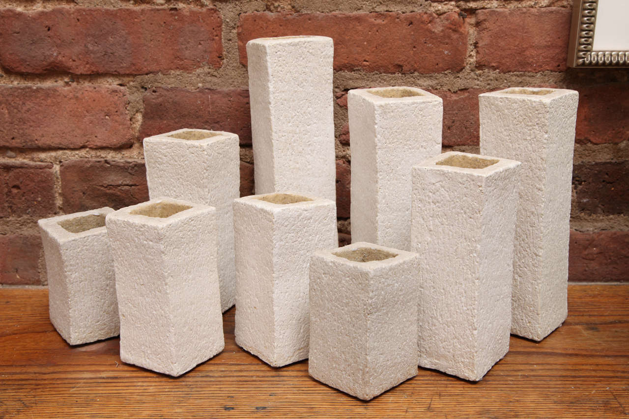 These white stoneware sculpture vases can be very playful depending on how they are displayed. They can be aligned or floating, as a group, or individually.
They are handmade and have two different textures. The outside is rough, while the inside