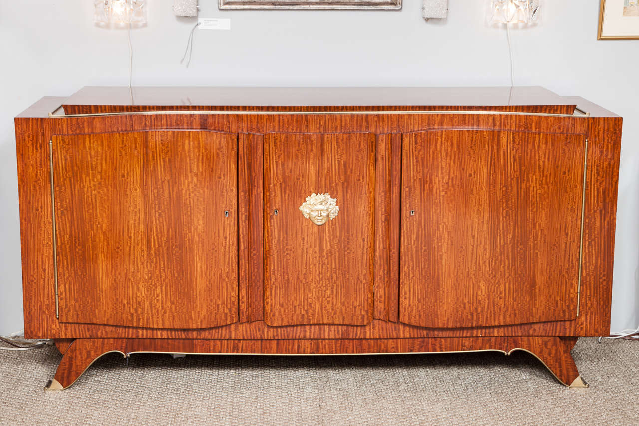 This exceptional rosewood and bronze buffet was designed and signed by Jules Leleu, the legendary French furniture designer of the last century. The buffet features three slightly curved doors, opening to inner shelves and two drawers. The superior