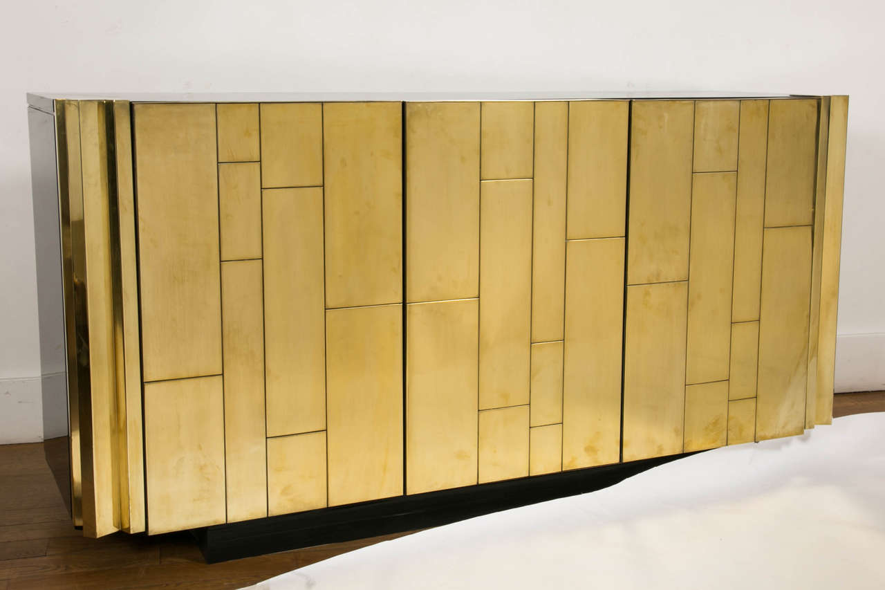 Important gilt brass and black lacquered sideboard, circa 1975, by Luciano Frigerio, Italy (1928-1999).
Black lacquered wood top, sides and back.
Three doors opening on mahogany inside with four drawers and one shelf.

Luciano Frigerio, a