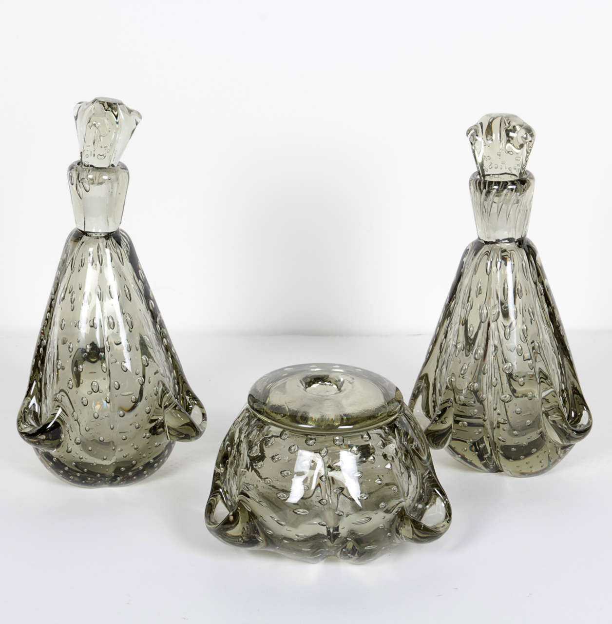 Beautiful and fine handblown Murano glass perfume set or vanity set. The glass has elegant free-form designs and is has details of bubble murines with a smokey grey cast. The set is comprised of two bottles or decanters with tops and a lidded bowl.