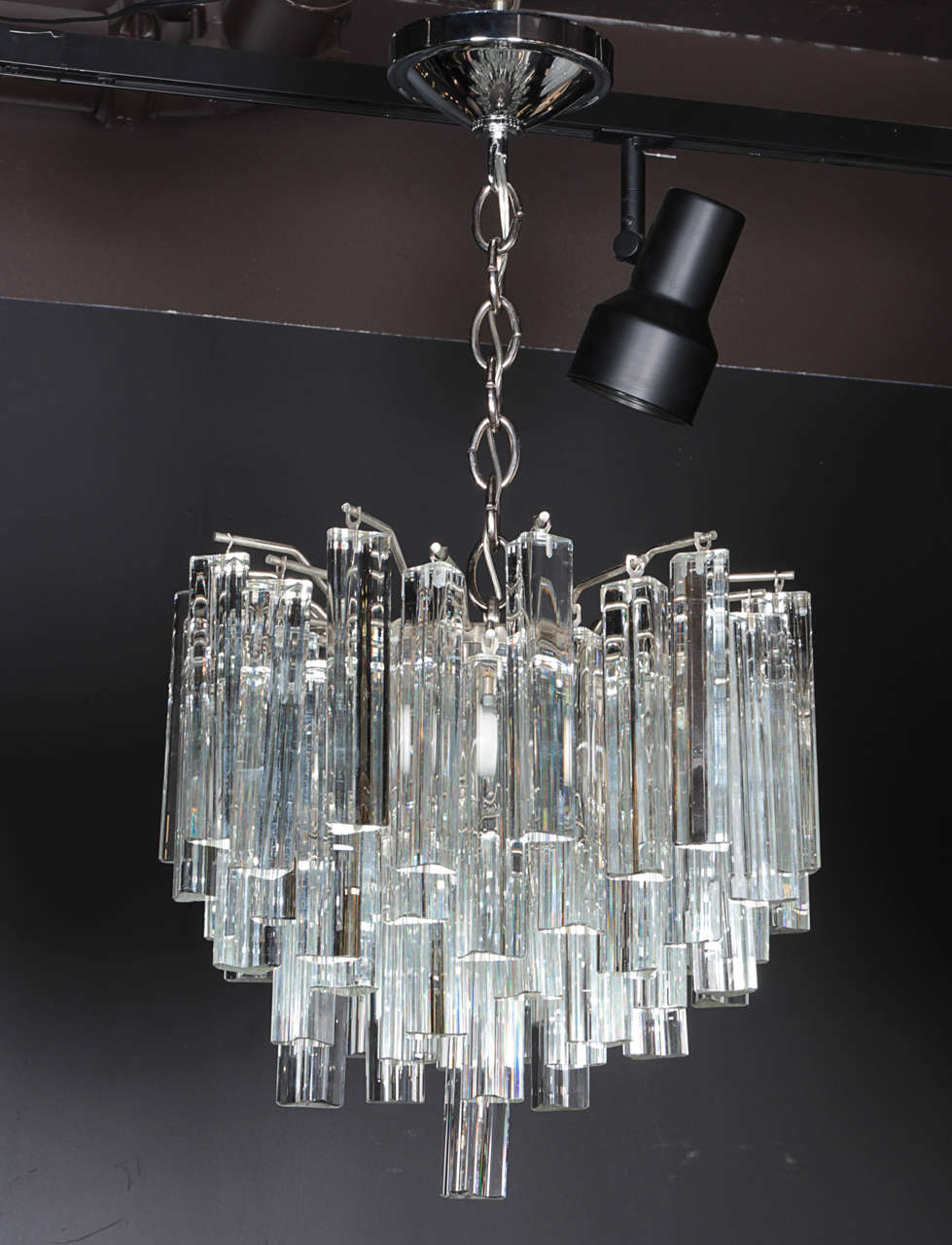 Gorgeous small-scale chandelier by Venini for Camer. Chandelier has multiple tier design comprised of trihedral crystal prisms throughout. The fixture has a chromed steel frame with polished chrome canopy and fittings. Fitted with four lights