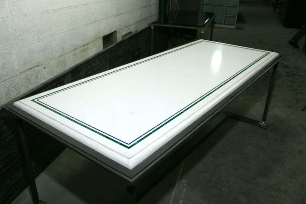 This fine marble topped table is crafted in the neoclassical style. The base is made of forged iron and accented with gilded bronze capitals and bases. The table top is a clear white marble with an ogee edge inlayed in a large border of malachite