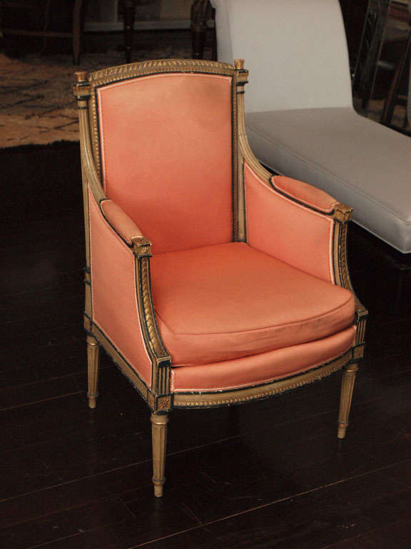 Two bergeres in the Louis XVI taste with ebonized and gilt beechwood frames, attractively carved and detailed; original upholstery in salmon-colored ottoman