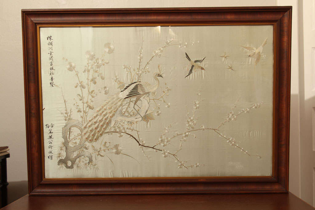Embroidered peacock on branch with other birds on silk wall hanging in glass frame. Possibly purchased at The Old World Shop in the 1960's at the now closed Frederick&Nelson department store in Seattle, Washington. Initials of K.W.C. and the word