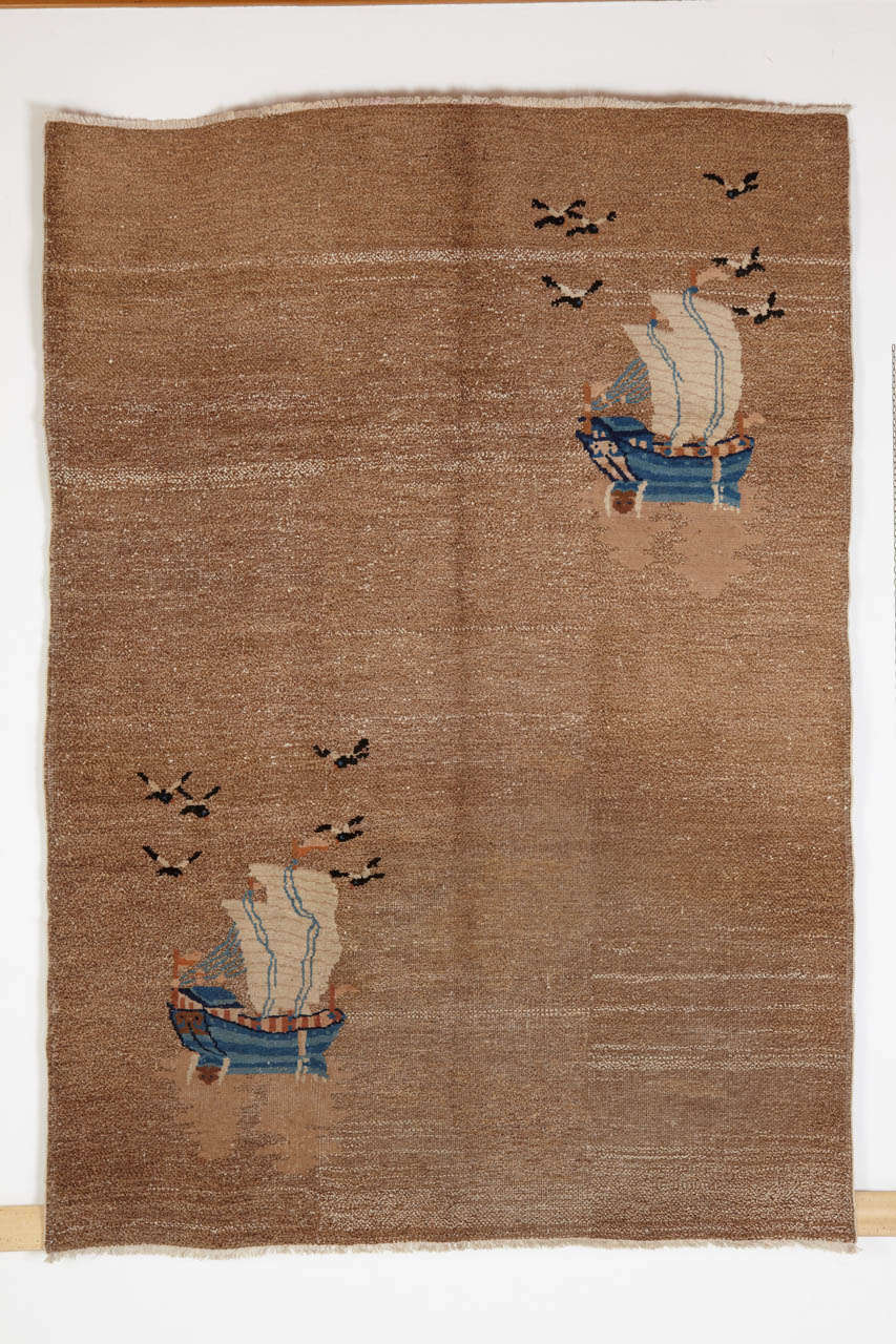 The specular arrangement of corner elements on an open field is a typical Art Deco carpet design concept. Here the artist was commissioned to depict a pair of sail boats each accompanied by a flock of seagulls, navigating an hypothetical sea