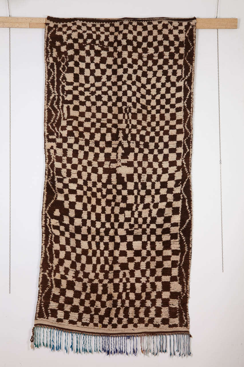 Originating from the Ourika valley, located in the central High Atlas of Morocco and known mostly for its flatweaves, this rug displays an abstract rendition of the checkerboard design, executed with ivory and chocolate brown wool. It is interesting