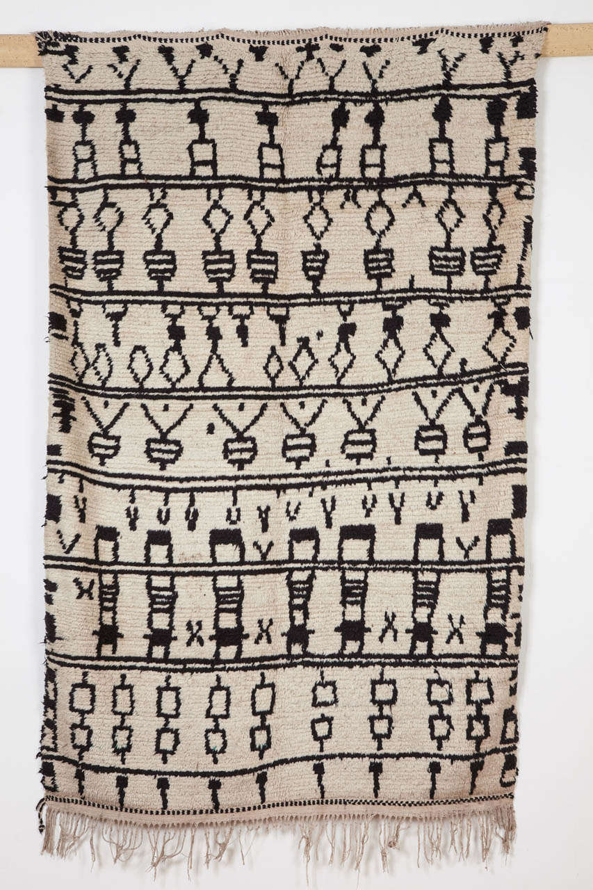 The rugs from the Azilal region, located in the central High Atlas of Morocco, are greatly appreciated for the naivete` of their patterns, often distinguished like in this example by an ivory/black color palette. Here the design is arranged over