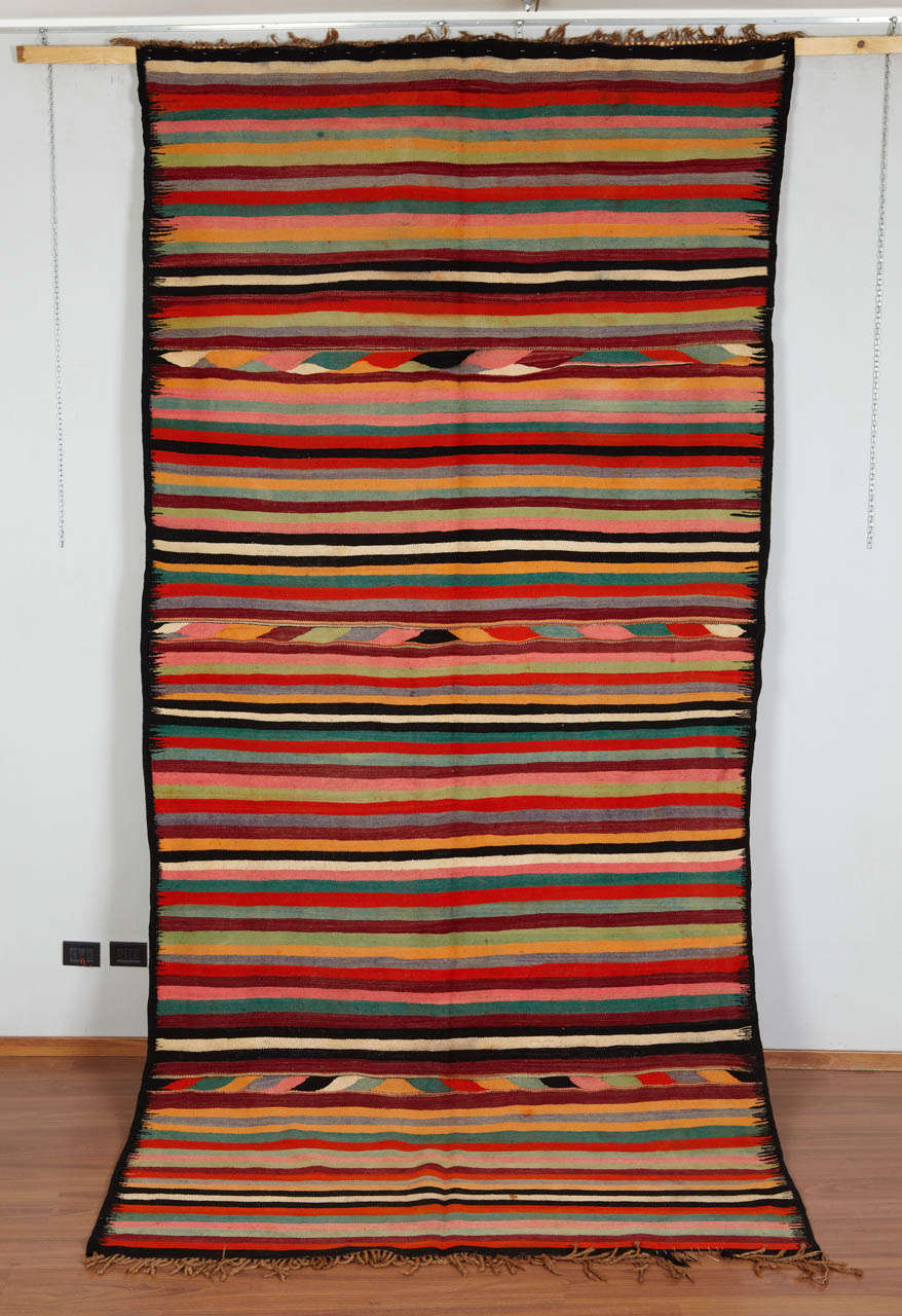 This is a multipurpose kilim - kind of Mergoum - coming from the south east of Algeria.
It's a Bedouin multicolored kilim. White lines are in camel wool. Some stripes reminds a running water motif. Colors are bright and vivid,this rug is not faded.