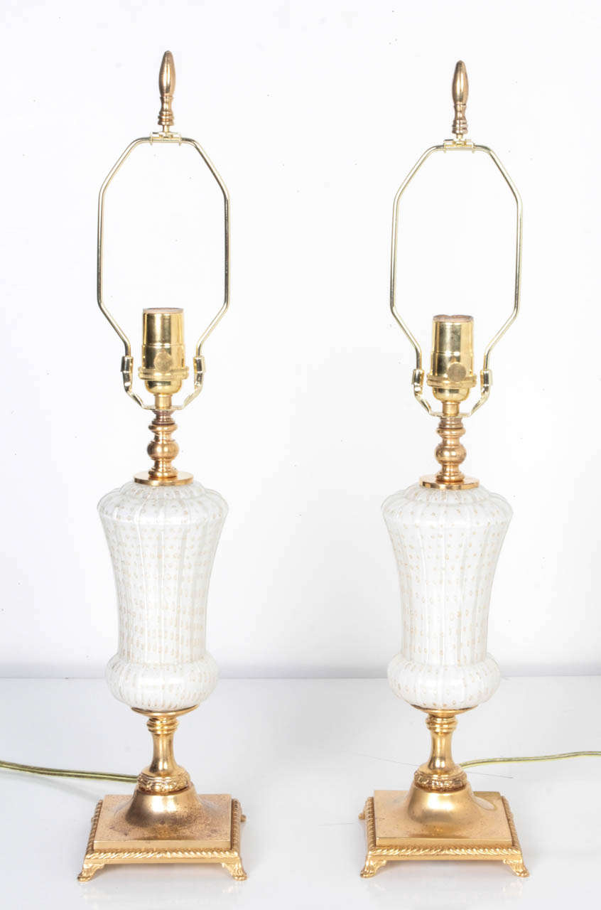 A pair of white and gold-flecked Murano glass lamps in their original age-worn gilded finish. Due to the antique nature of this fixture, there may be some nicks or imperfections in the glass.

Shades shown in secondary image are not included and