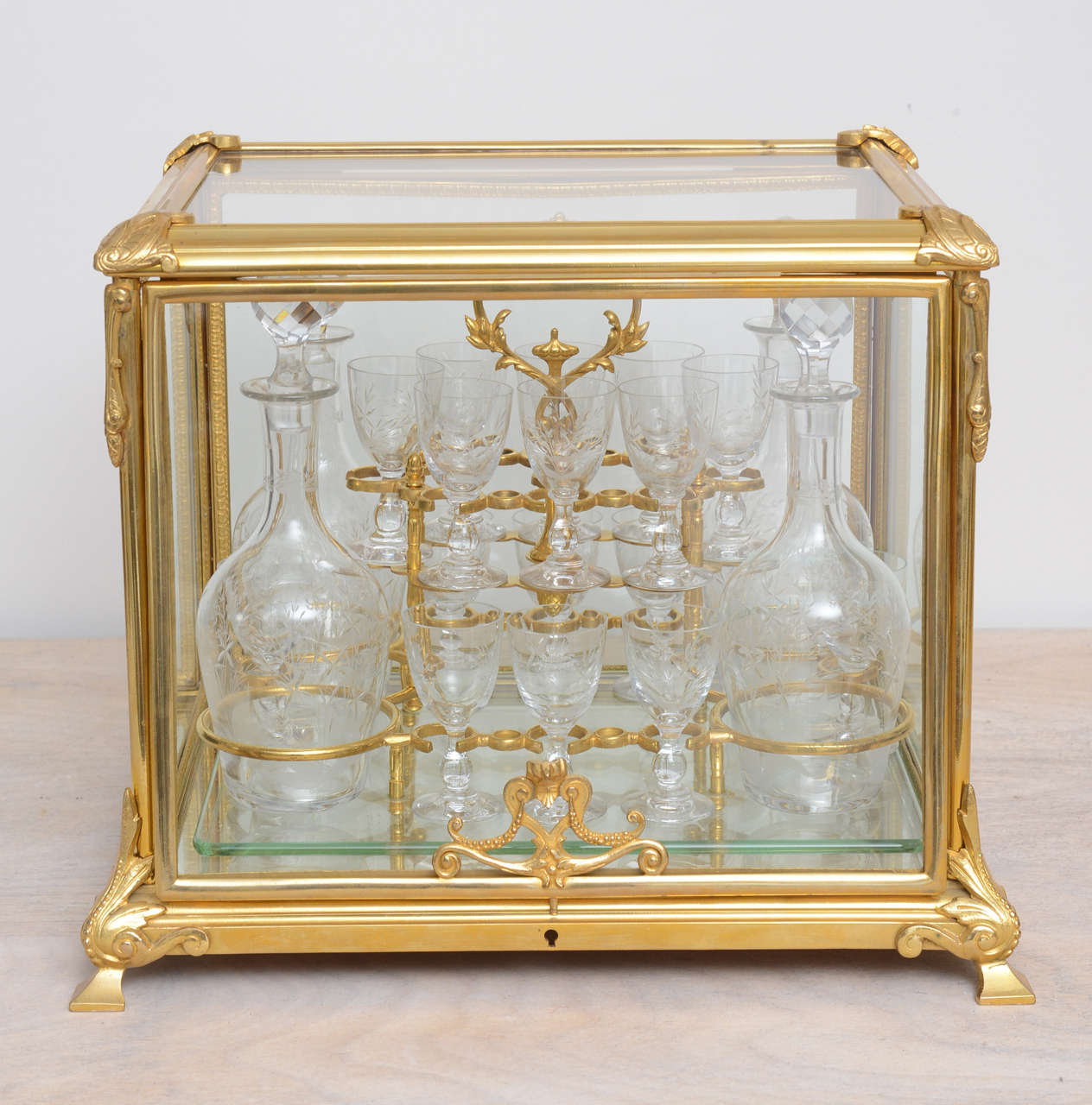 Fabulous original Tantalus consisting of four decanters and 14 glasses. Doré bronze case with mirrored bottom and glass sides and top.