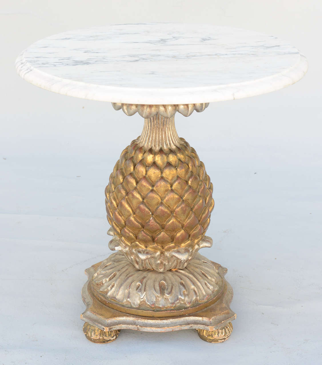 Accent table, having a round top of Carrara marble, on silver and gold giltwood base, carved in the form of a stylized pineapple, on molded plinth base.