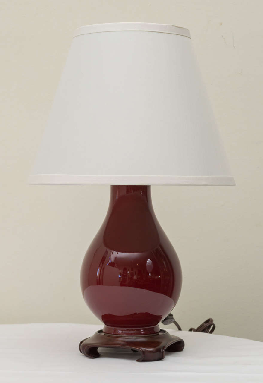Pair of  Chinese oxblood vases in modified form as lamps. Vases  reduced in height to create small bottle forms. Rewired with new sockets. On wood stands. No shades. Republic period.