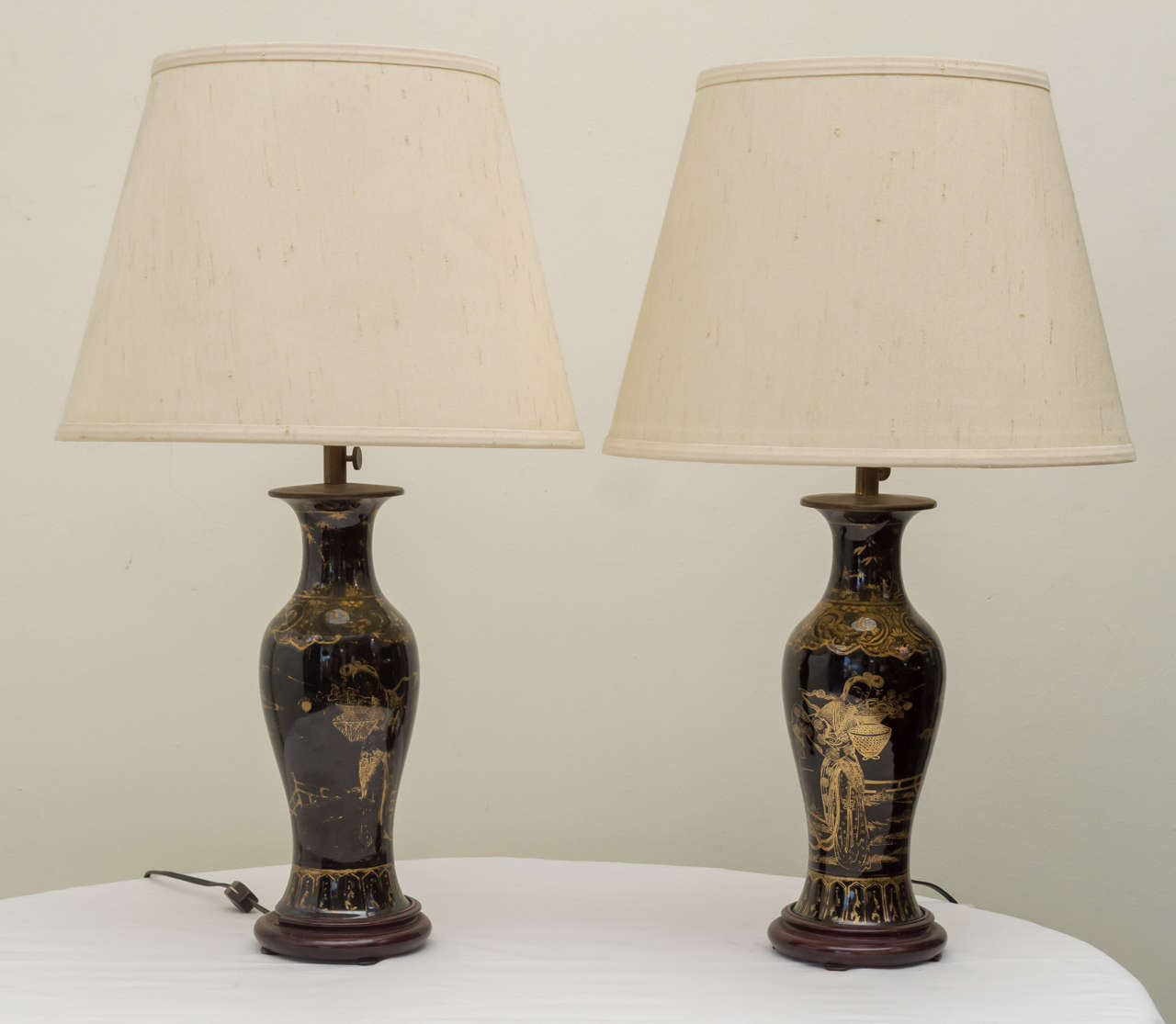 Pair of late Quig Period mirror black porcelain baluster form vases as lamps. Gold gilt decoration. Custom adjusting height, 2 light cluster and wood bases. Older custom worn silk shades. Overall height 24.5 inches, shade is 14inches in  diameter.