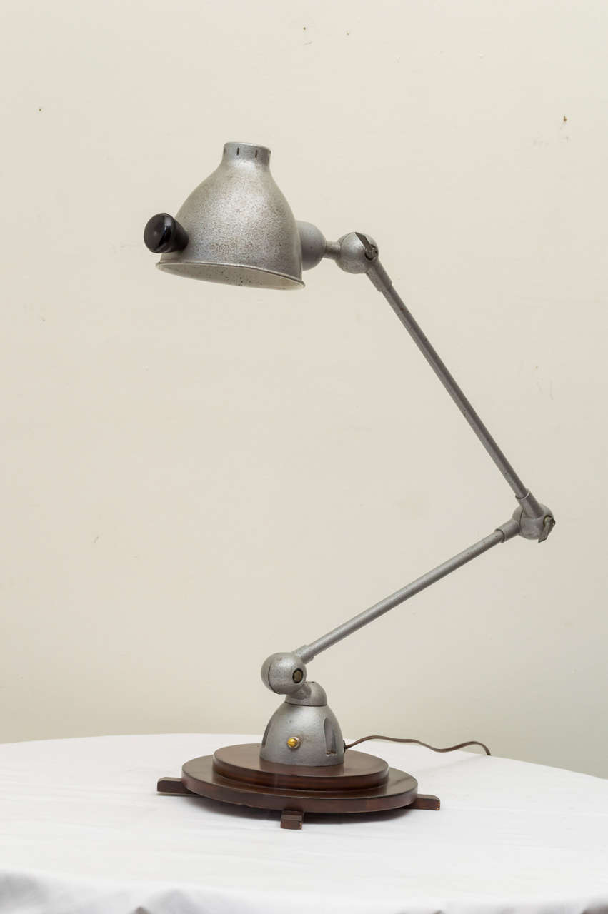 20th century French Industrial adjusting arm lamp mounted to a wooden Deco base. Originally wall-mounted. Silver paint. All rewired with a new socket. Arms are 25/27 high when bent.