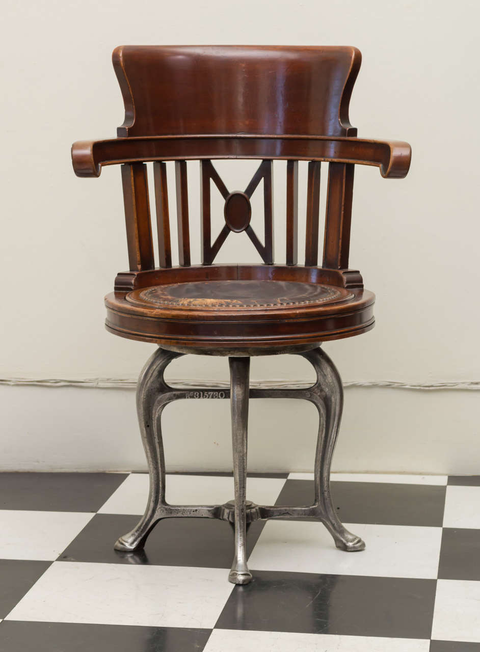 Late 19th c American ship's chair in mahogany and a nickel iron swivel base. A unique nautical form. The mahogany frame in the form of a stool with a back, arms and old leather seat. Compact and comfortable. Heavy cast iron cabriole leg base with