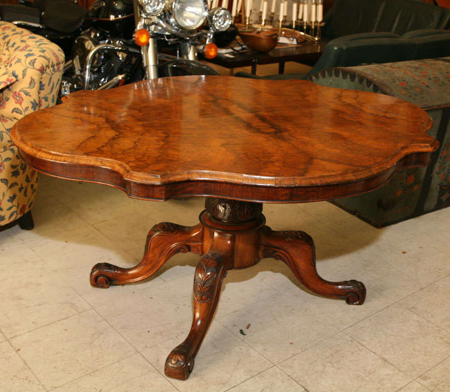 English center or breakfast table, with lozenge- shaped tilt-top in highly figured walnut, the quadrepod base carved with leaves and flowers.