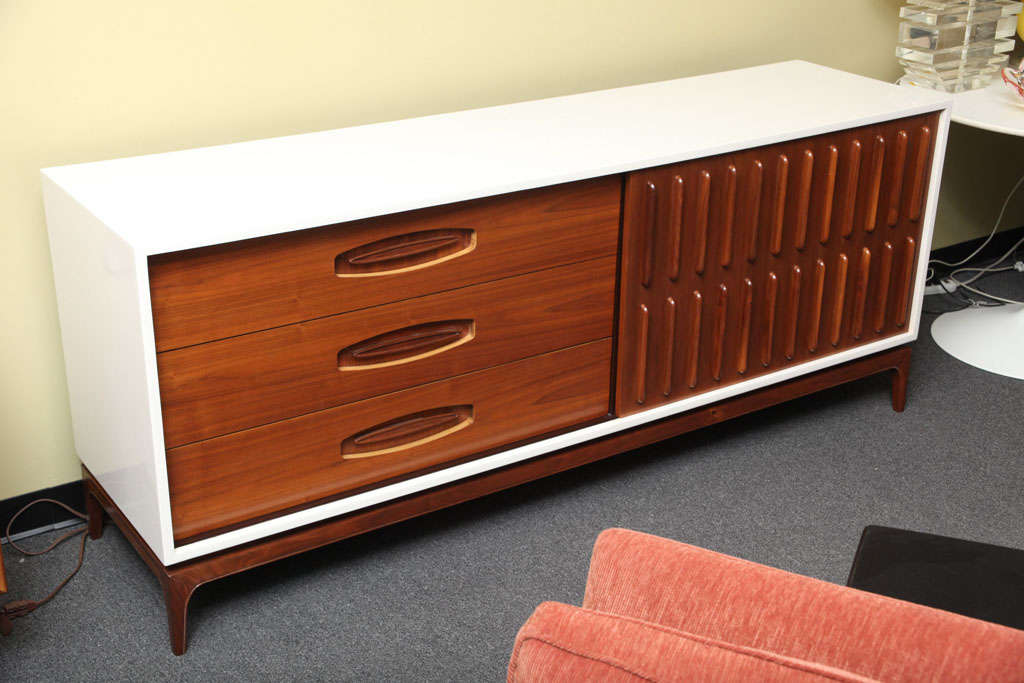 .SOLD FEBRUARY 2011..Very sleek mid-century styling in this Credenza Dresser with a white polished lacquer body and three large walnut drawers to one side and scuptural sliding door with walnut half drawers behind.  All above a rich shaped walnut
