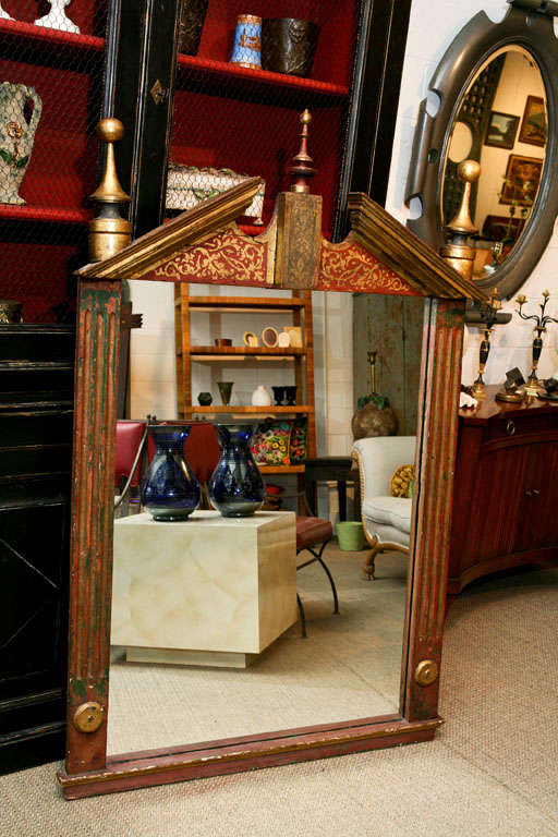 Here is a great mirror featuring architectural elements and painted detail 

crowned by three beautiful gold leafed finials.