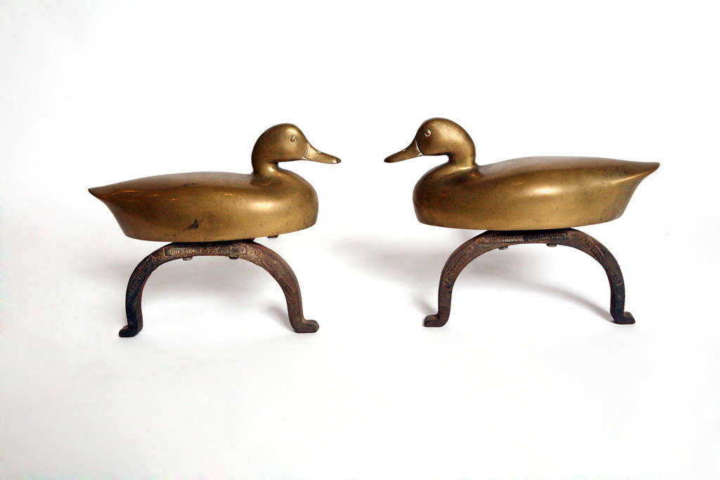Wonderful pair of brass andirons.  These are opposing brass ducks, on cast iron bases.  These were made by the Richard F. H. Clancy foundry in Needham, Mass.  The cast iron base is marked by the foundry.