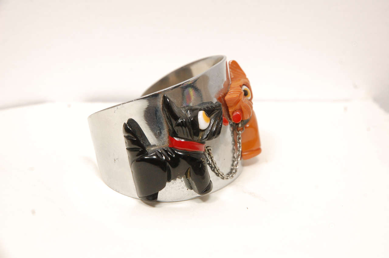 This is pure art deco from the 30's.  The cartoony black and yellow
dogs with the chain leash between them are set into a chrome
bracelet. It is marked depose.