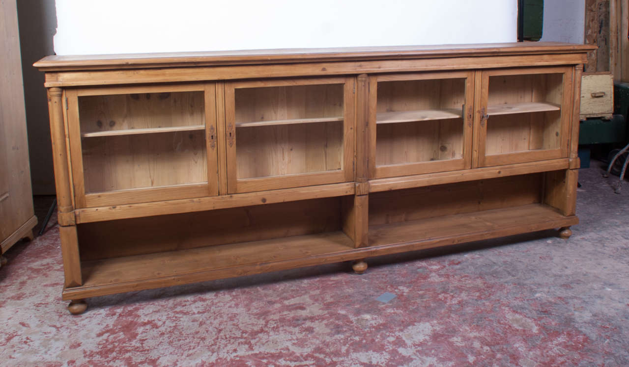 A beautiful long low bookcase featuring four glazed doors and two open shelves flanked by split balusters.