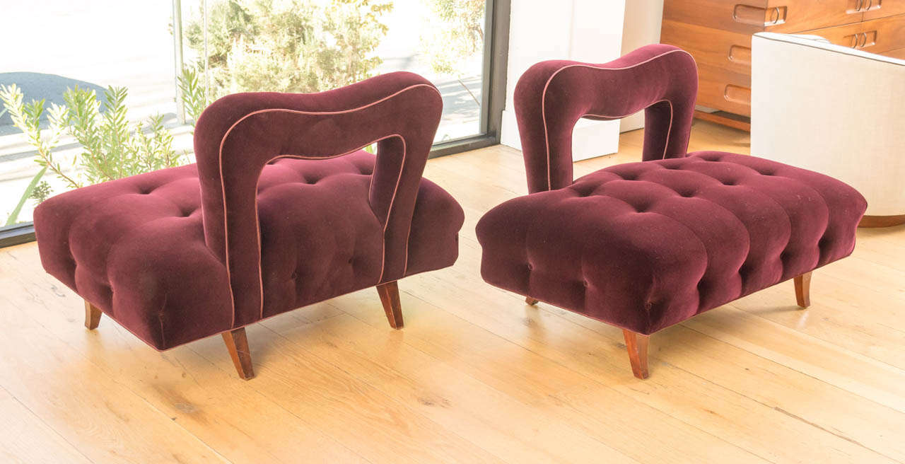 A pair of open backed lounge chairs with tufted seats and leather trim. New wool velvet upholstery and mahogany feet.