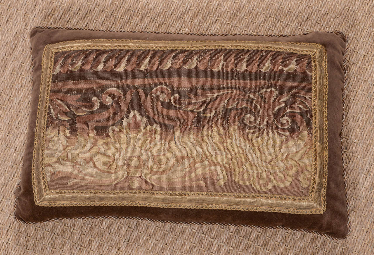 18th century tapestry fragment bordered with vintage gold metallic trim on a pillow composed of velvet in rich milk chocolate hue. Pillow is custom-made with braid trim running along edge. Down filled.