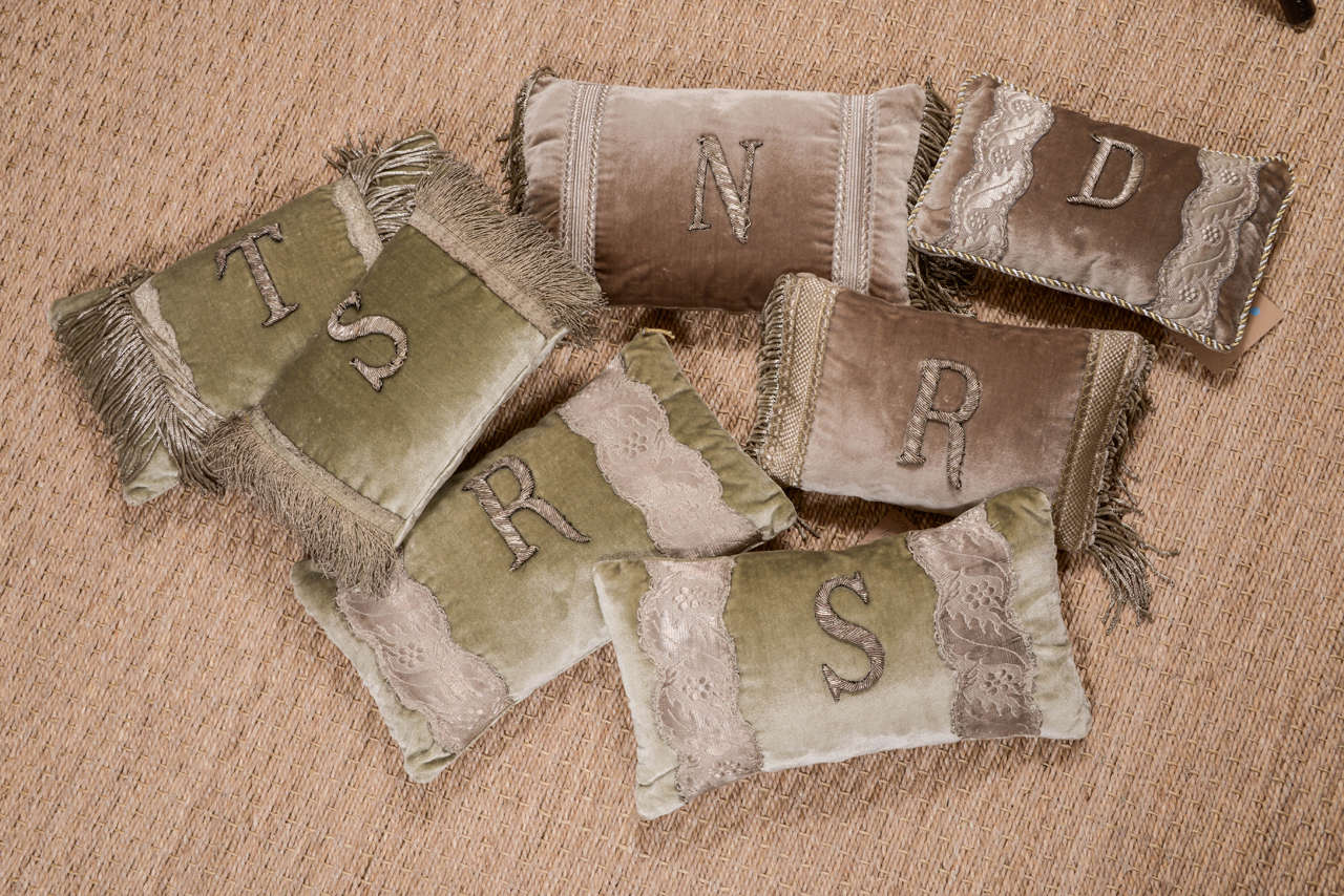 Assortment of 19th century metallic initial pillows framed by metallic French Galon or fringe on silk velvet. Pillow sizes vary from 6