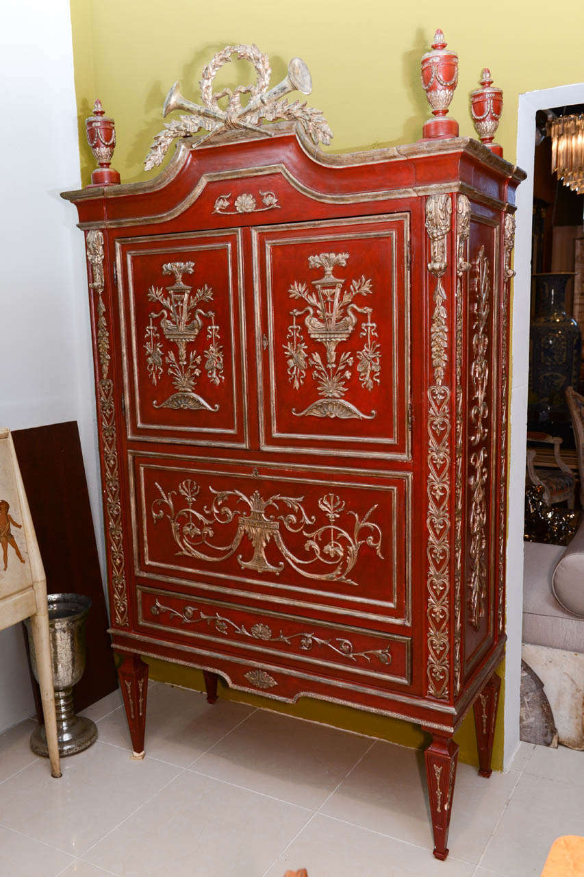 Overall painted scarlet with carved neoclassic motifs all-over topped with urns and cresting.