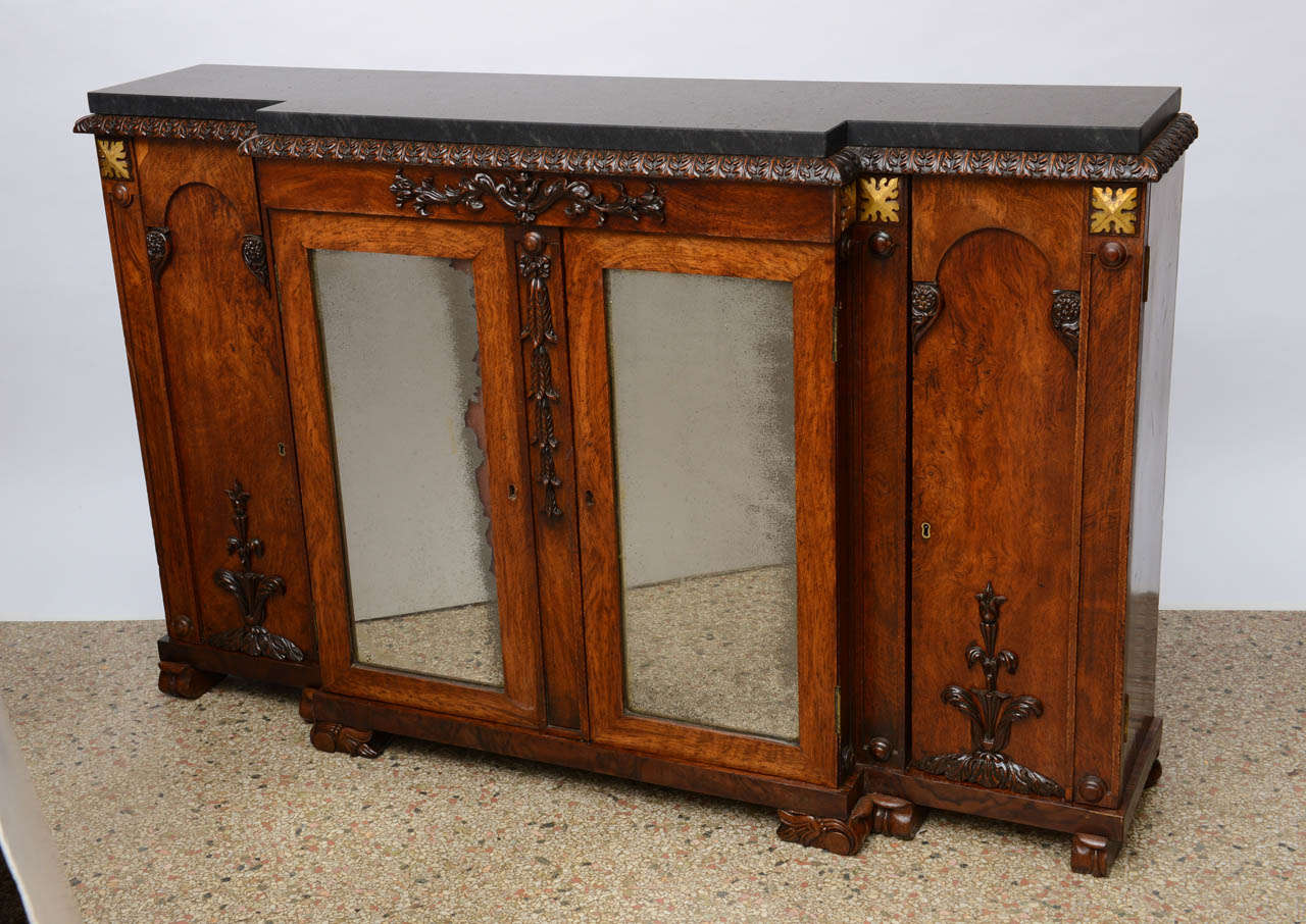 English Regency sideboard; rosewood with a black marble top.  Original center pair of mirrored doors flanked by flat panels with hand carved decorations. Beautiful carving throughout with interior shelves.  Original restored finish.

Originally $