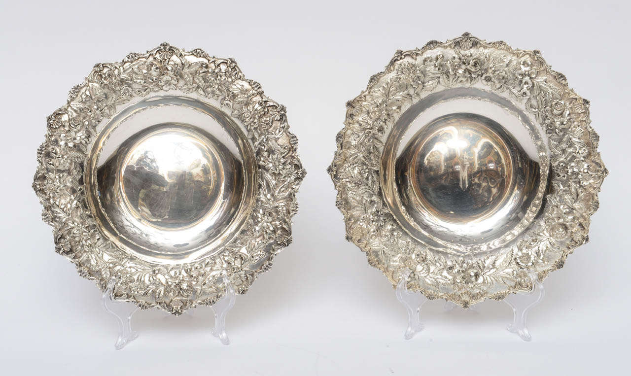 Pair of Sterling Silver Bowls by Samuel Kirk & Son, Inc., Baltimore, Maryland.  Shallow bowls each having an ornate wide repousse floral border.  One is engraved 