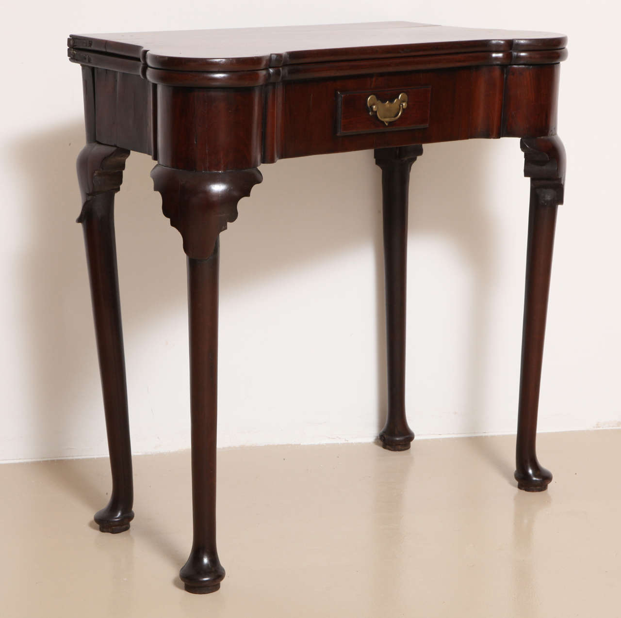 With outset corners opening to a suede-lined interior fitted with guinea wells and corners finished for candle stands; over a frieze drawer and raised on cabriole legs with lamb's tongue-carved knees and terminating in pad feet.