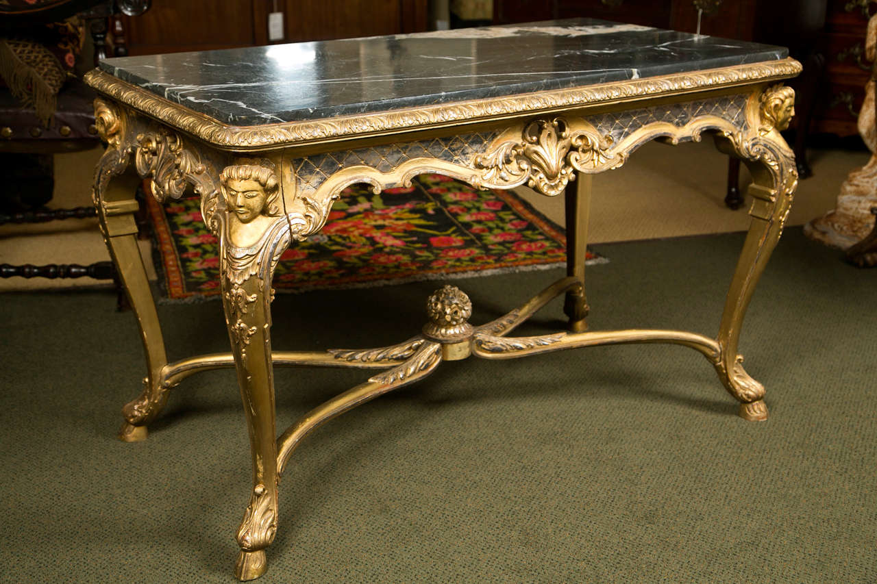 Une table centrale en argent doré avec un plateau en marbre noir.
