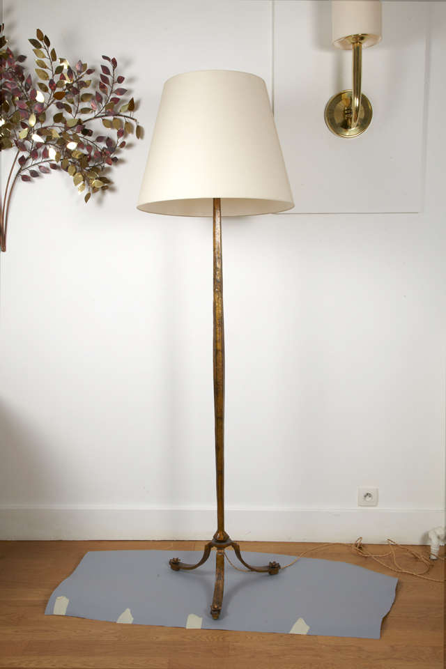 Gilt patinated floor lamp by Maison RAMSAY, with a slightly barrelled cantwise shaft, lightning with cup and three lamps, resting on a tripod base, feet ornated with flowers. Cream white fabric shade.
Shade diam.55 cm. Total height with shade 185