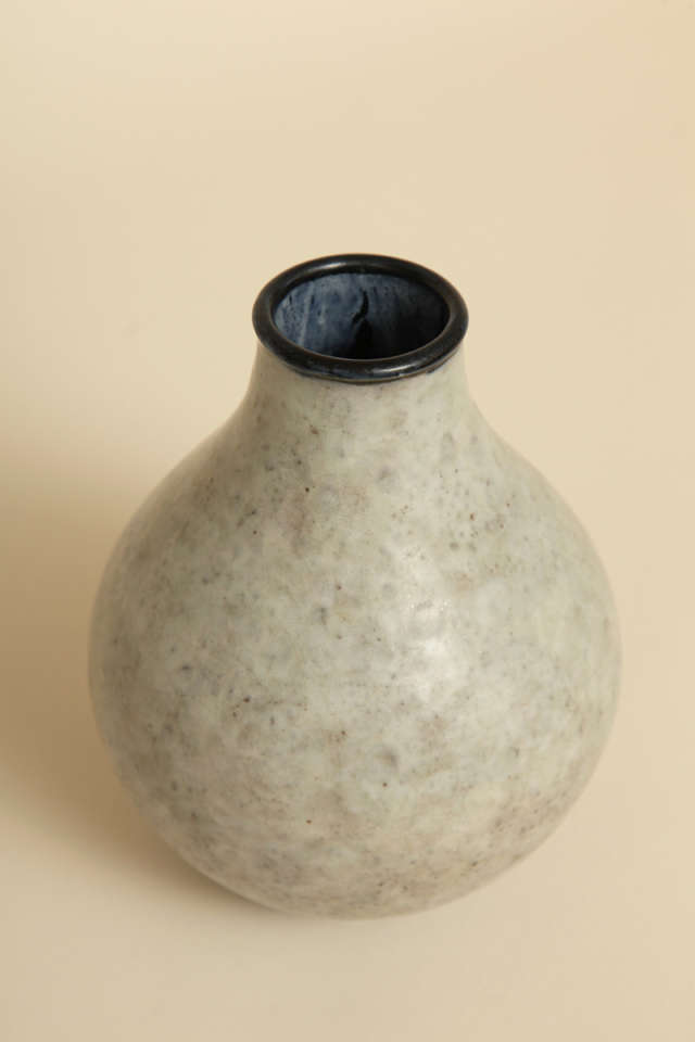 Ce vase en grès d'E'mile Decoeur (1876-1953) présente une bouche à glaçure noire bleutée, un col et un corps à glaçure blanche et grise, et un pied à glaçure noire.
Signé : 