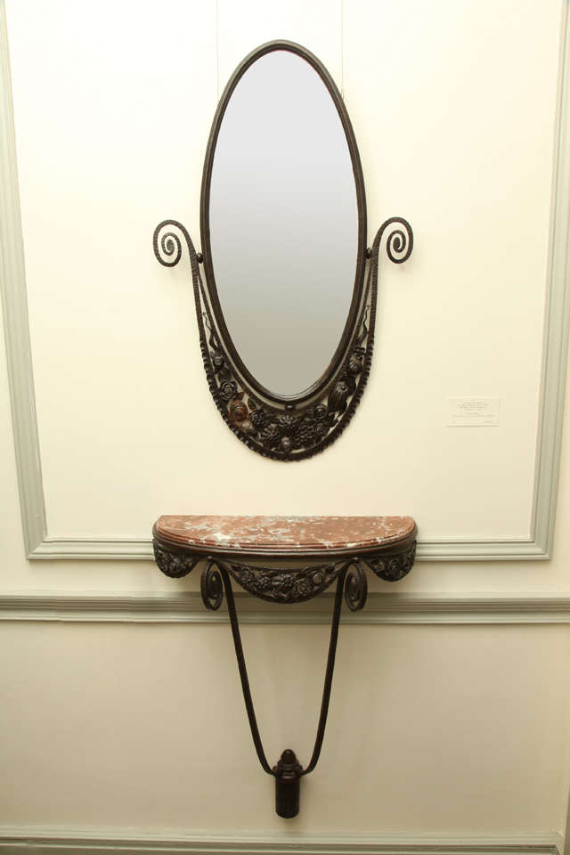 This slender console by Edgar Brandt (1880–1960) has a red marble top above a wrought iron floral and foliate skirt. The oval wrought iron mirror above has a matching scrolling floral and foliate crest.
Stamped: E. Brandt

Console: Height: