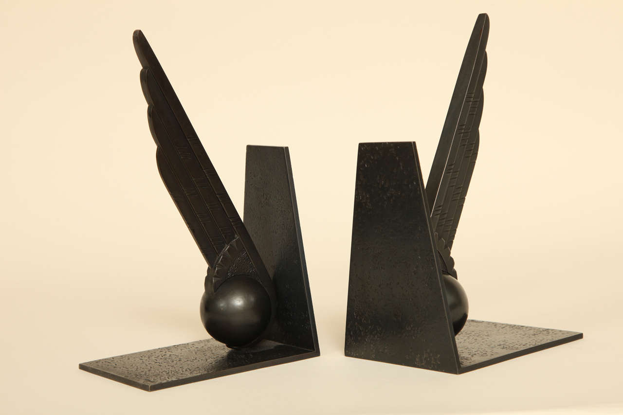 These wrought iron bookends are in the form of a stylized wing and ball on an angular support mounted on a rectangular base.
These bookends were designed to commemorate the first non-stop east to west crossing of the North Atlantic by plane, which