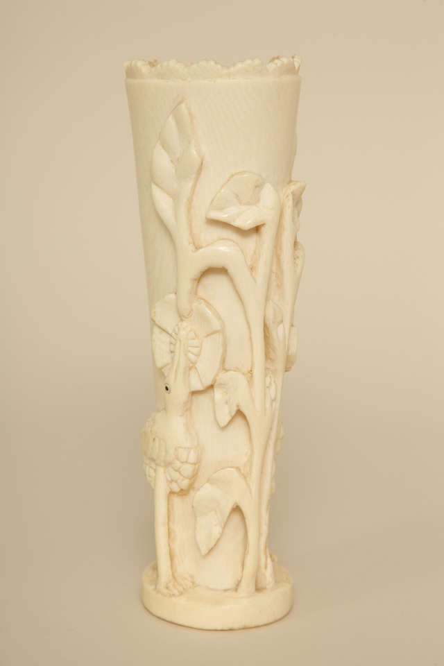 Bone vase with sculpted birds and trees.