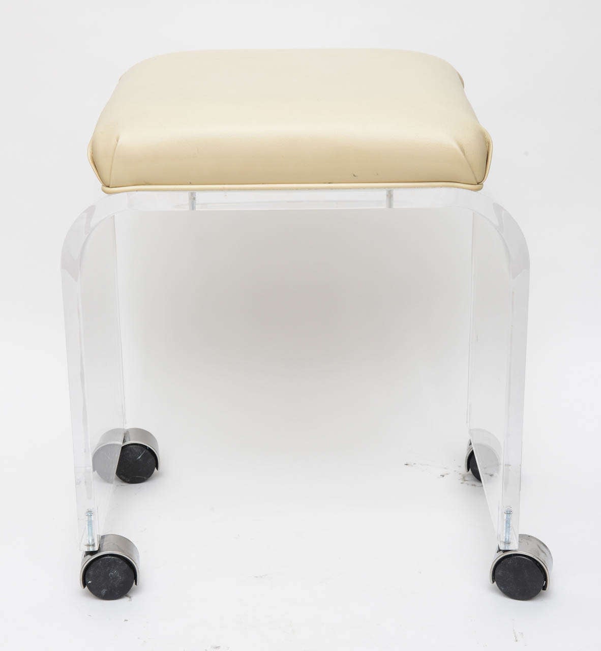 This vanity stool with its clean-lined waterfall form is very much in the style of pieces created by Charles Hollis Jones in the 1970s. The piece has a beigey vinyl upholstered seat which makes for and easy clean-up when used as a vanity stool. The