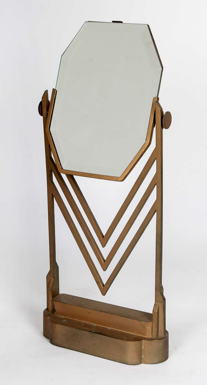 Jock Peter(1889-1934) Designer 
Eleanor Lemaire (Designer)
Feil & Paradise Company
Bullocks Wilshire (Los Angeles, CA)

Art Deco Table Top Jewelry Salon Mirror circa 1928.

Gold toned cast bronze with a stepped lozenge shaped base and an