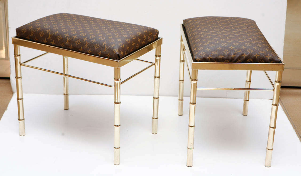 Pair of faux Louis Vuitton vinyl ottomans with brass plated bamboo legs. *Slight mark on the upholstery of one ottoman.