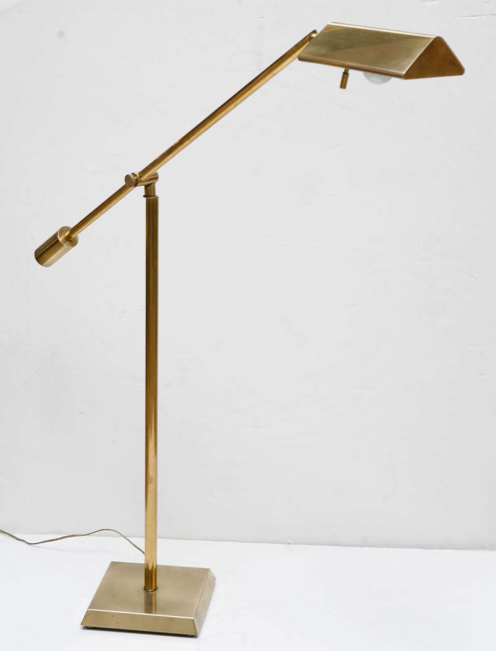 Adjustable brass floor lamp by Chapman.  A single counter balanced arm sits on a square beveled base.
