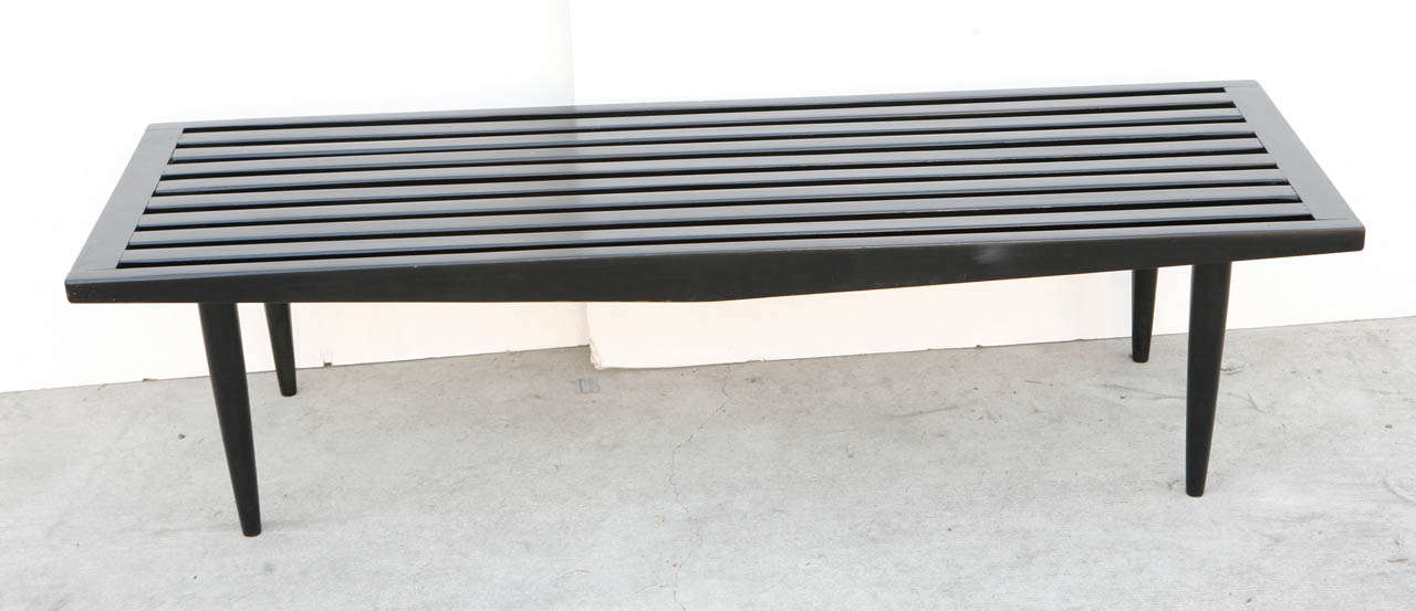 Nelson style black wood slatted bench with tapered legs.