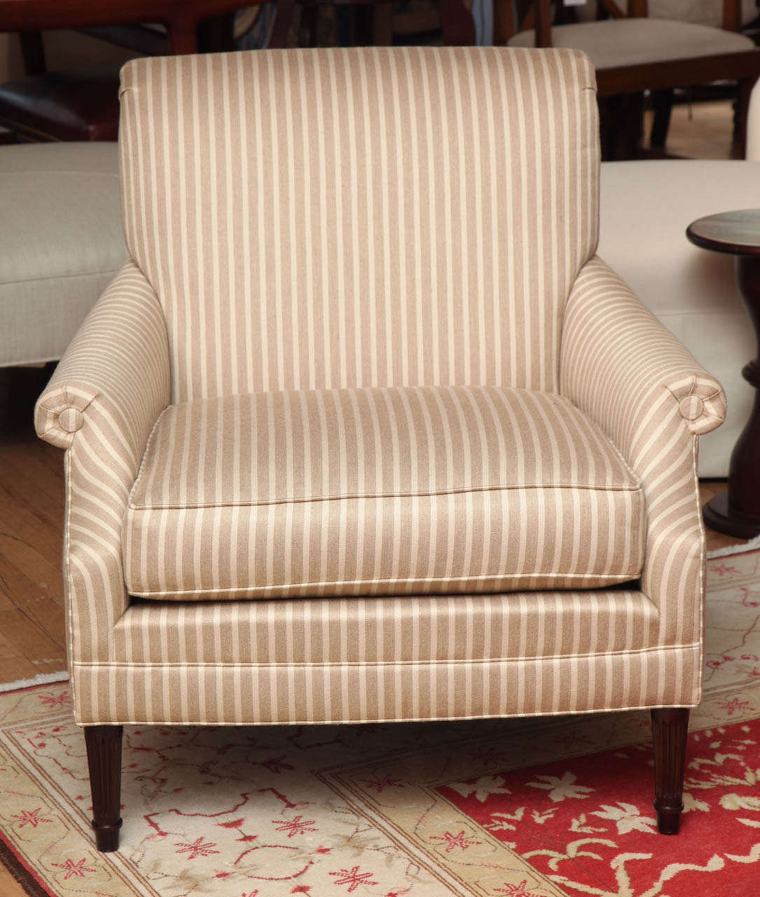 Audrey Lounge Chair by Mariette Himes Gomez for The Hickory Collection with Spring down Seat Cushion, Dark Walnut Legs, and Upholstered in a Beige on Beige Striped Sunbrella Fabric.