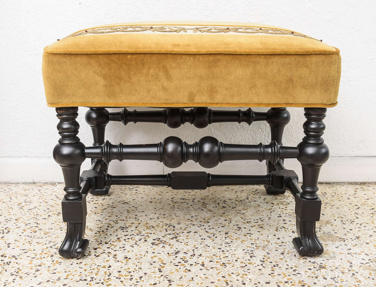 Pair of 19th century Italian stools with an ebony dark finish on the wood frame which is detailed with a Flemish-Foot . The pieces are upholstered in a gold Velvet fabric with an insert banding, which has a stylized floral embroidered detail of