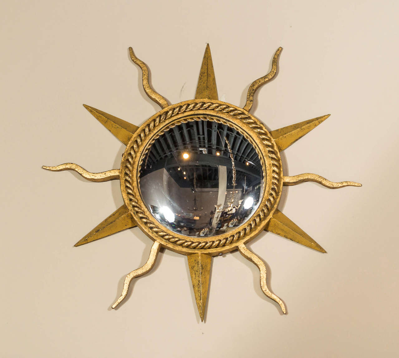 Attributed to Gilbert Poillerat, a hand-forged, gilt, wrought iron starburst, convex mirror with alternating serpentine rays,
France, circa 1940.