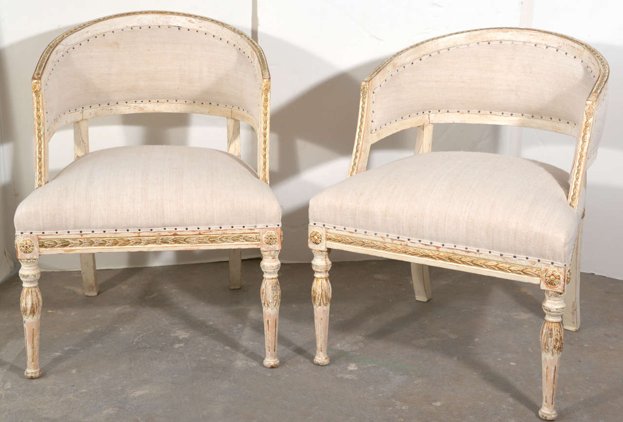 Very pretty barrel back chairs covered in antique linen.  They have been scraped and still have hints of gold highlights on the leaf motif design.