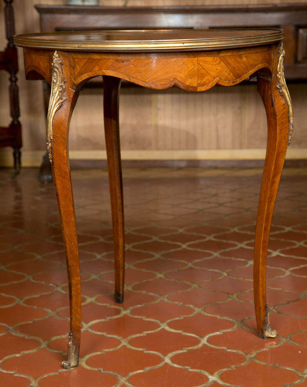This dynamic little table in kingwood features a parquetry top, brass ring surround and ormolu knee mounts on the three cabriole legs. The shaped apron is cross banded in kingwood as well and it offers a bit of depth to the top that gives it just