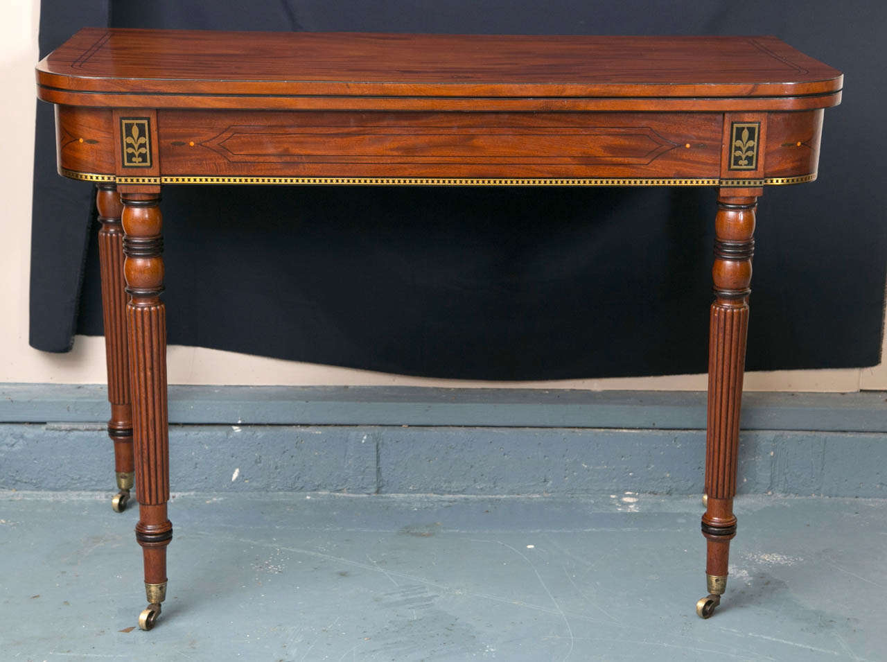 From the deeply whorled grain to the brass inlay and ebonized accents, this flip-top tea table epitomizes English Regency style. Both back legs swing to support the open top, which opens to a generous, near square 40” by 38”. One the finest tea